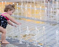 little girl playing on water feature